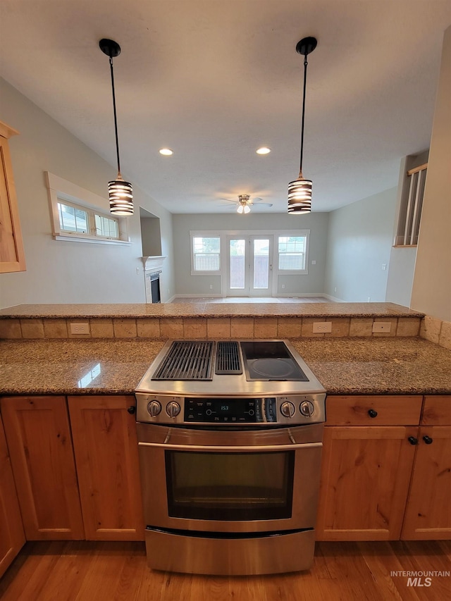 kitchen featuring light stone counters, decorative light fixtures, light wood finished floors, and stainless steel electric range