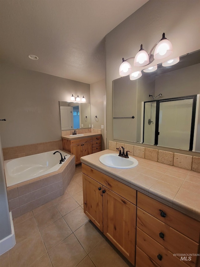 full bath with tile patterned floors, a garden tub, a sink, and a stall shower