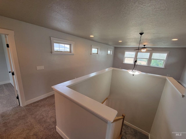 corridor with recessed lighting, dark carpet, an upstairs landing, baseboards, and a textured ceiling