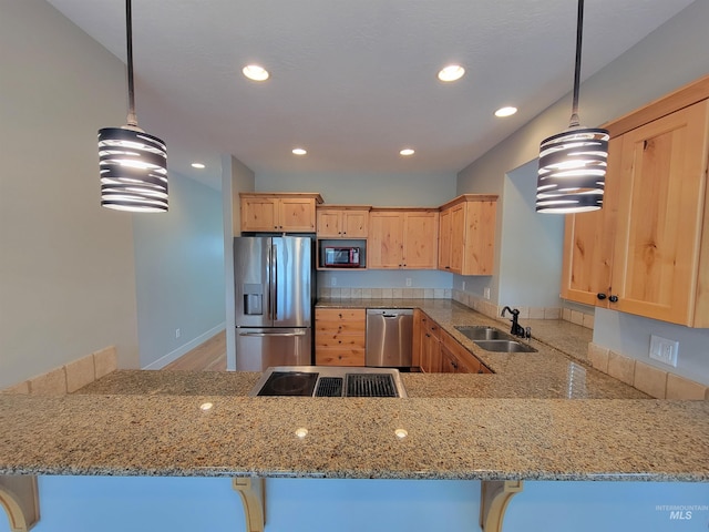 kitchen featuring stainless steel appliances, light brown cabinets, a sink, light stone countertops, and a peninsula