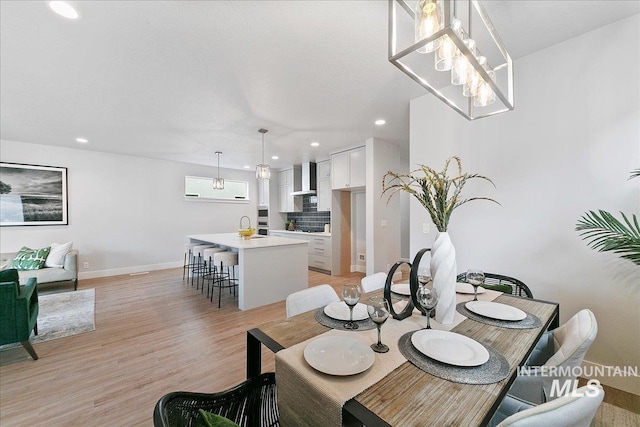 dining room featuring an inviting chandelier, recessed lighting, baseboards, and light wood-style floors