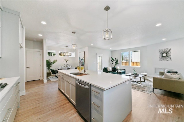 kitchen with dishwasher, light countertops, light wood-style floors, and a sink