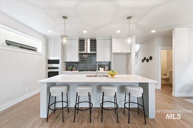 kitchen with an island with sink, light countertops, appliances with stainless steel finishes, a kitchen bar, and tasteful backsplash