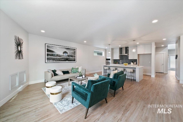 living area with recessed lighting, baseboards, and light wood finished floors