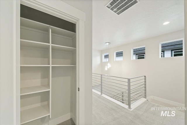 interior space with visible vents, baseboards, recessed lighting, carpet flooring, and an upstairs landing