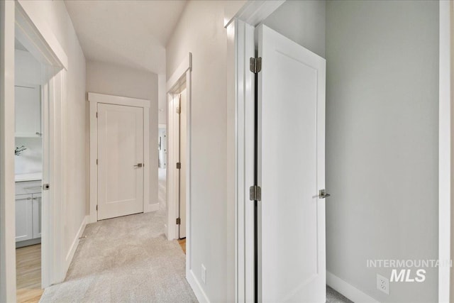 hall featuring baseboards and light carpet