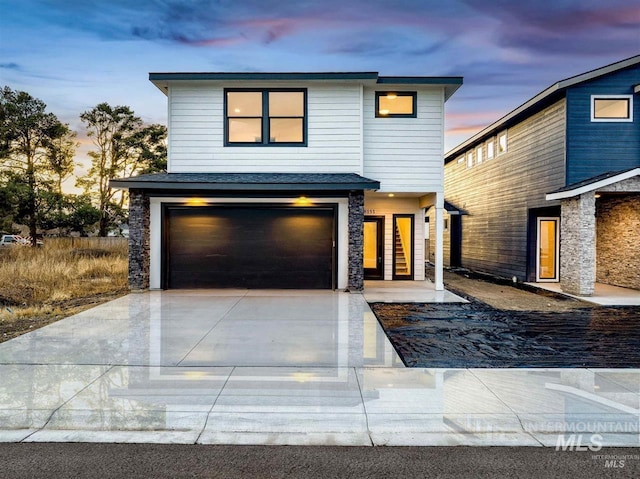 view of front of house with a garage, stone siding, and driveway