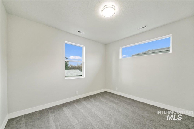 unfurnished room featuring visible vents, baseboards, and carpet flooring