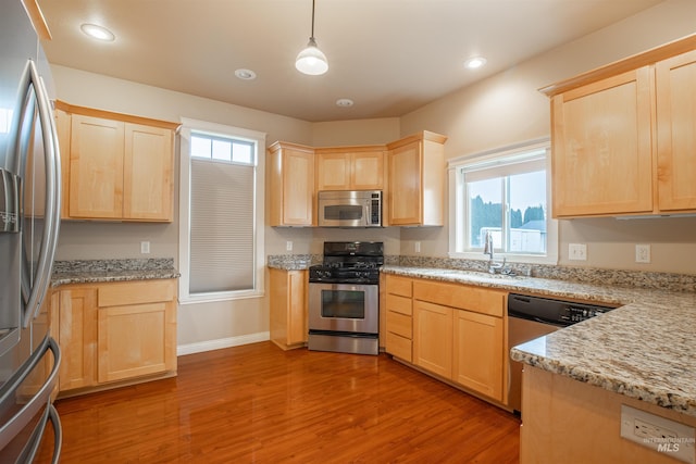 kitchen with dark wood-type flooring, light brown cabinets, sink, stainless steel appliances, and pendant lighting