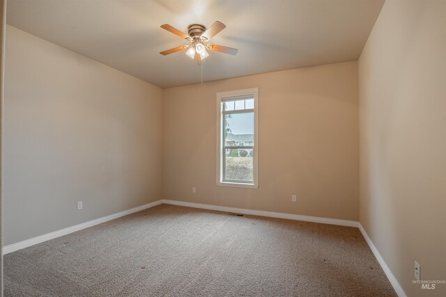 spare room with dark carpet and ceiling fan