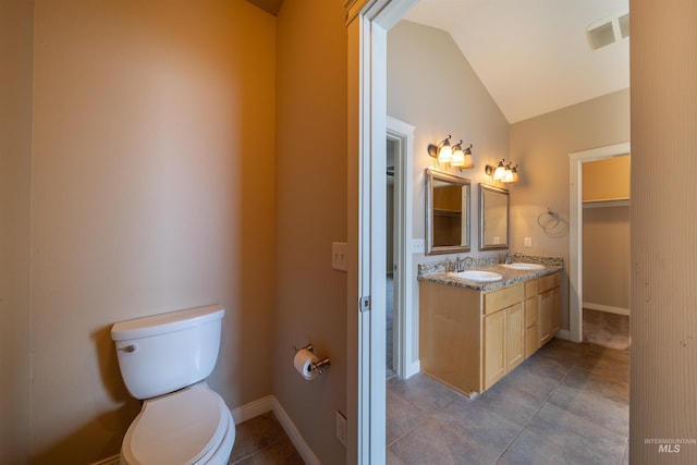 bathroom with dual vanity, tile floors, toilet, and vaulted ceiling