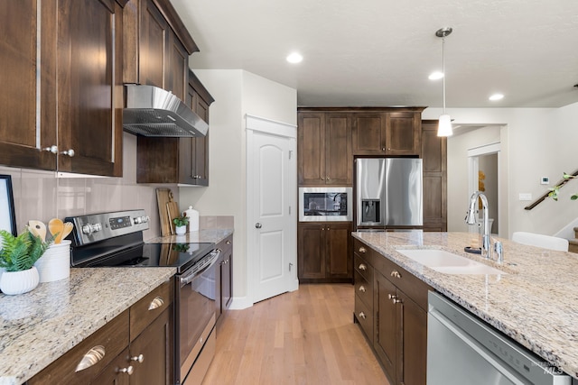 5826 E Playwright St, Boise, ID 83716 - kitchen with appliances with stainless steel finishes, wall chimney range hood, light wood-style flooring, dark brown cabinets, and light stone counters