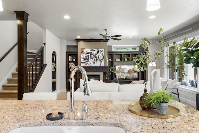 5826 E Playwright St, Boise, ID 83716 - kitchen featuring ceiling fan, a glass covered fireplace, recessed lighting, light stone counters, and a textured ceiling