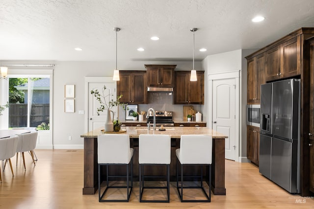 5826 E Playwright St, Boise, ID 83716 - kitchen featuring stainless steel appliances, light wood-type flooring, dark brown cabinets, a kitchen breakfast bar, and recessed lighting