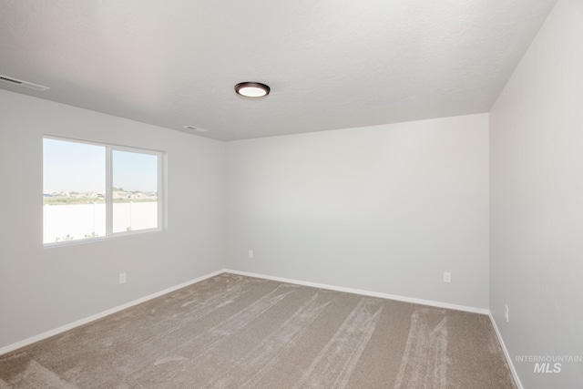 unfurnished room featuring carpet and a textured ceiling