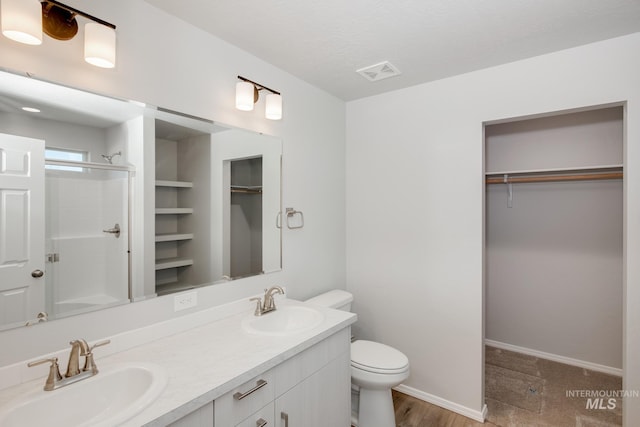 bathroom featuring vanity, hardwood / wood-style flooring, toilet, and a shower with door