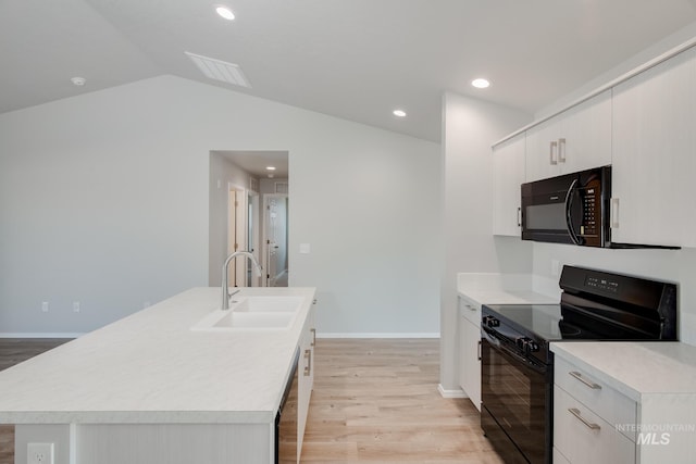 kitchen featuring sink, vaulted ceiling, a kitchen island with sink, black appliances, and light wood-type flooring