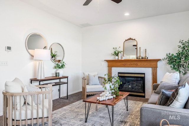 living room with a tiled fireplace, carpet floors, and ceiling fan