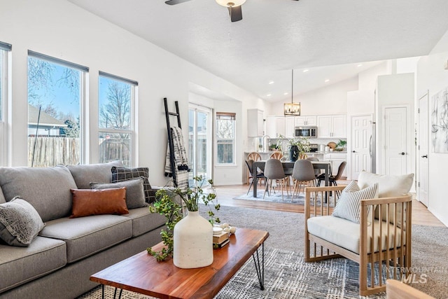 living room featuring ceiling fan, lofted ceiling, and light wood-type flooring