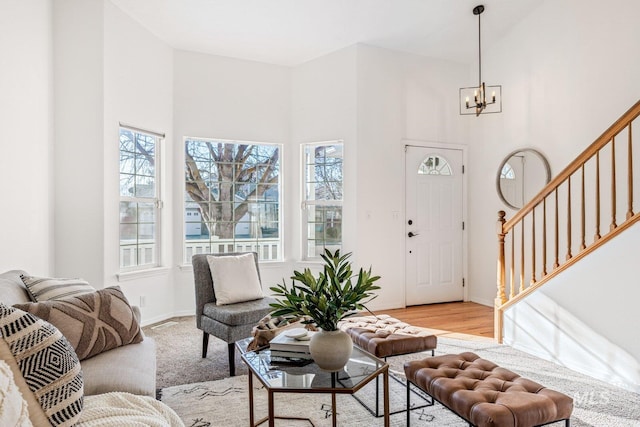 living room featuring light wood-type flooring, plenty of natural light, a chandelier, and a high ceiling