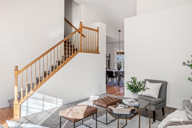 living room featuring a towering ceiling, wood-type flooring, and a notable chandelier