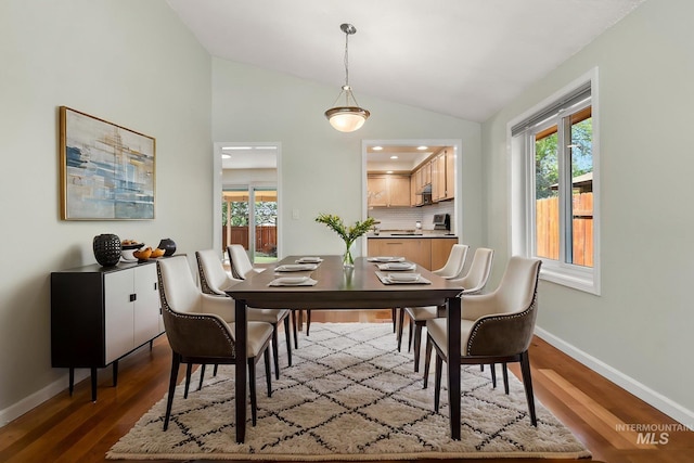 dining area with baseboards, plenty of natural light, vaulted ceiling, and dark wood finished floors