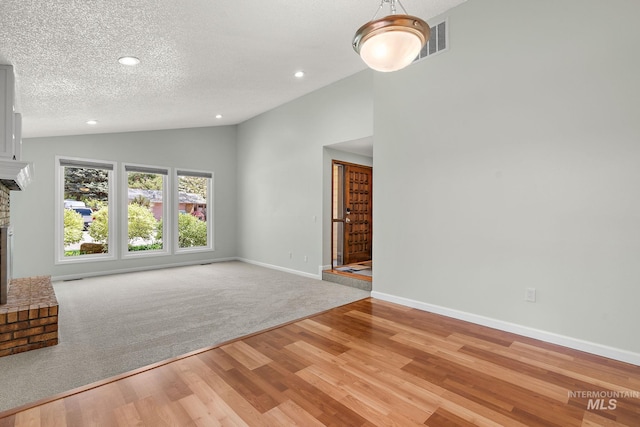 unfurnished living room with light wood-style floors, a brick fireplace, recessed lighting, lofted ceiling, and visible vents
