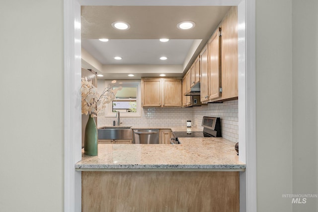 kitchen featuring appliances with stainless steel finishes, tasteful backsplash, a sink, light stone counters, and recessed lighting