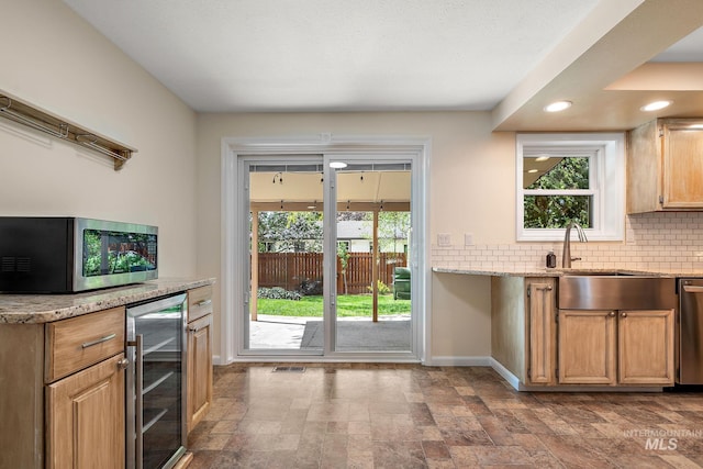 bar featuring decorative backsplash, beverage cooler, baseboards, a sink, and stainless steel appliances