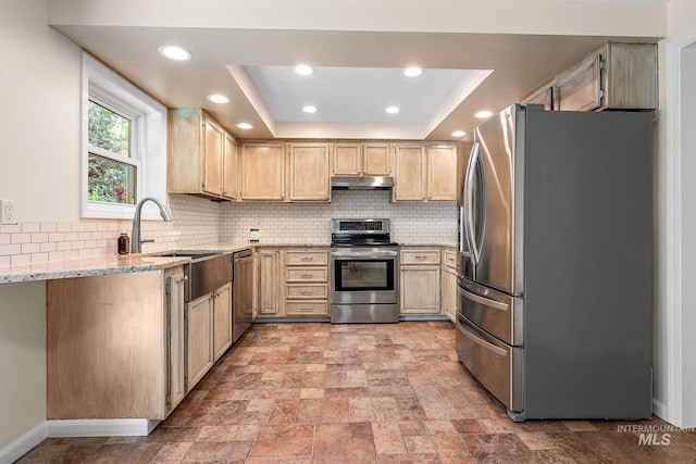kitchen featuring appliances with stainless steel finishes, tasteful backsplash, under cabinet range hood, and light stone counters