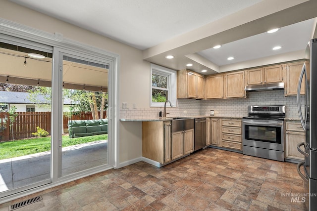 kitchen featuring visible vents, stone finish floor, under cabinet range hood, appliances with stainless steel finishes, and backsplash