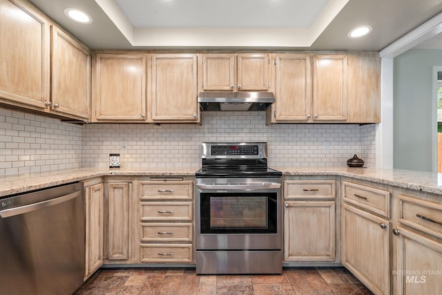 kitchen with appliances with stainless steel finishes, light brown cabinets, recessed lighting, under cabinet range hood, and a tray ceiling