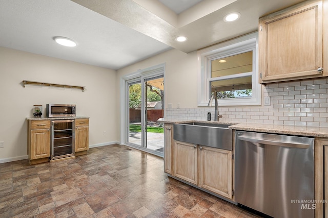 kitchen with appliances with stainless steel finishes, a sink, light brown cabinets, beverage cooler, and stone finish floor