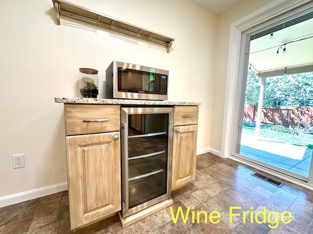 bar with baseboards, stainless steel microwave, beverage cooler, and visible vents