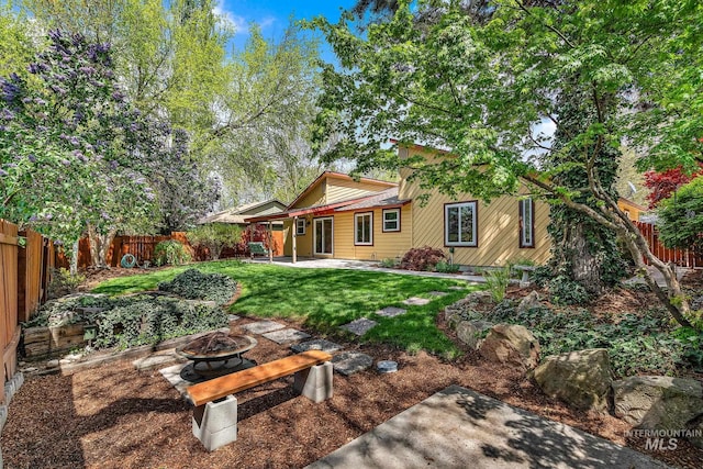 back of property with a fenced backyard, a yard, an outdoor fire pit, and a patio area