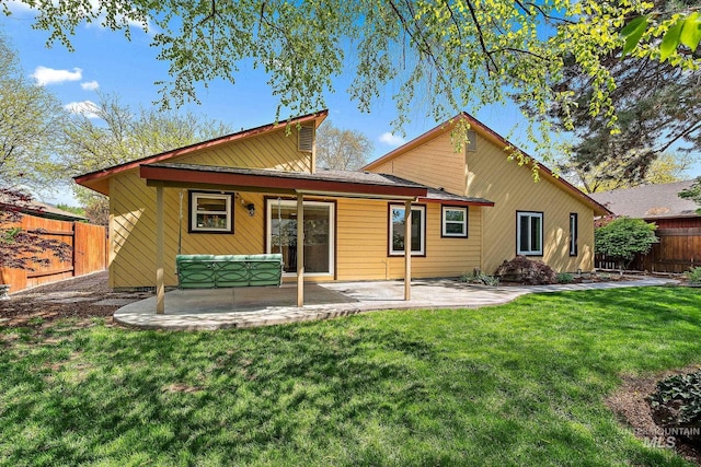 rear view of house featuring fence, a patio, and a lawn