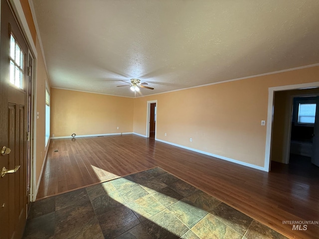 empty room featuring ceiling fan, a textured ceiling, wood finished floors, baseboards, and crown molding