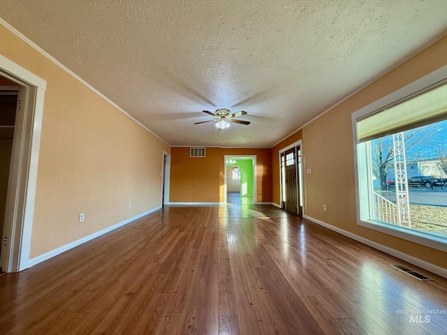 unfurnished room with ornamental molding, baseboards, visible vents, and hardwood / wood-style floors