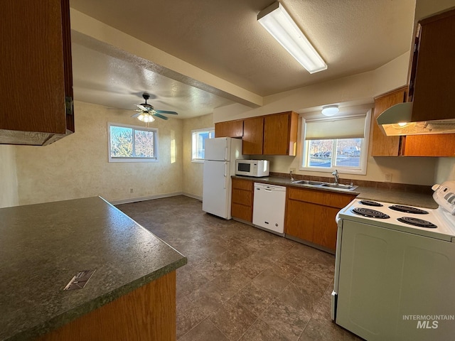 kitchen featuring white appliances, dark countertops, brown cabinets, a textured ceiling, and a sink