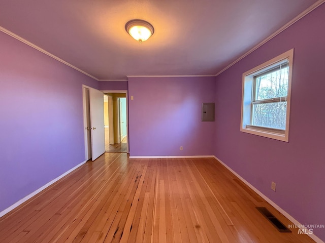 empty room with visible vents, baseboards, electric panel, hardwood / wood-style floors, and crown molding