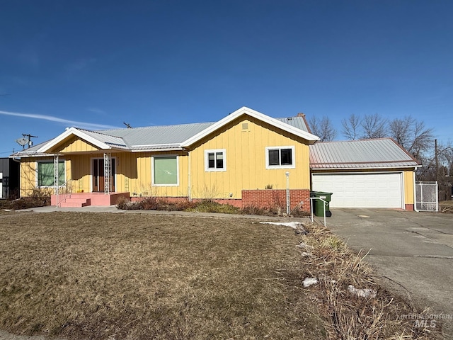 ranch-style home with metal roof, aphalt driveway, an attached garage, and brick siding