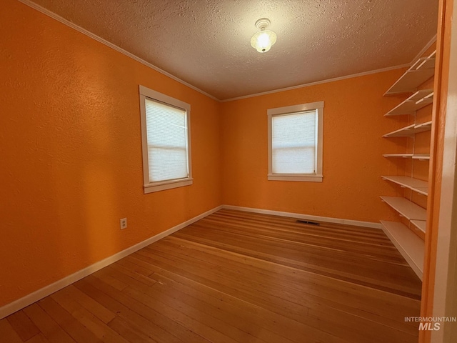 unfurnished room featuring ornamental molding, plenty of natural light, and hardwood / wood-style flooring