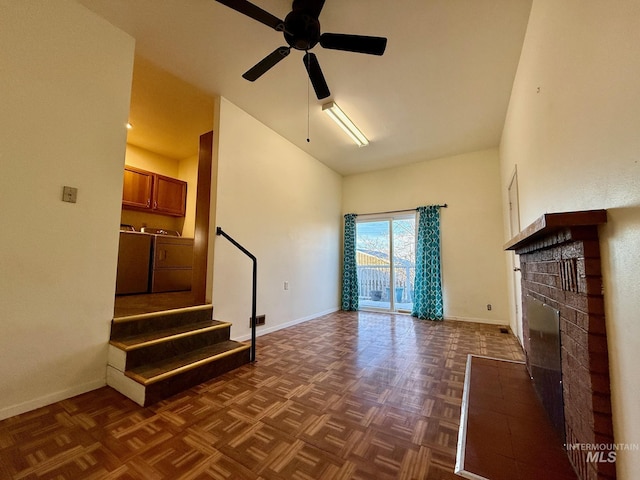 unfurnished living room featuring baseboards, a ceiling fan, washing machine and clothes dryer, stairs, and a fireplace