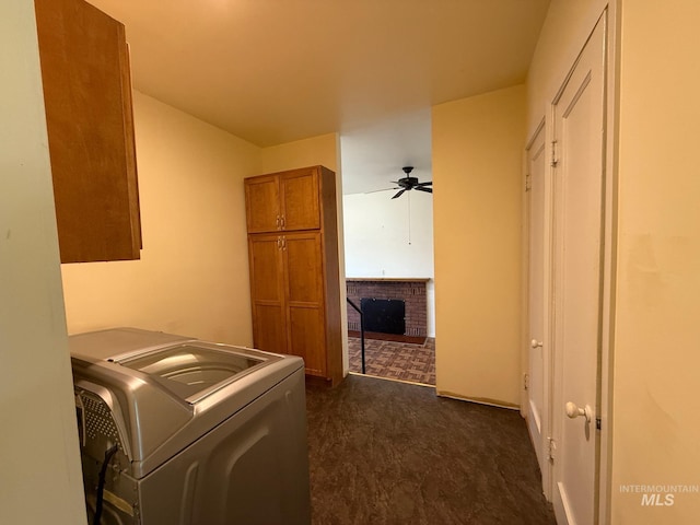 clothes washing area featuring ceiling fan, a brick fireplace, cabinet space, washer / clothes dryer, and dark carpet