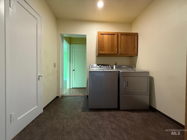 laundry area featuring washing machine and dryer, cabinet space, and baseboards