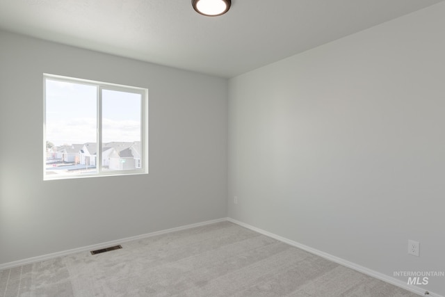 empty room with light carpet, visible vents, and baseboards