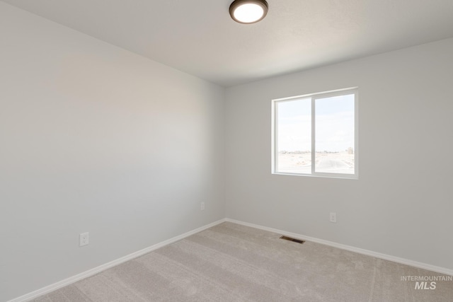 empty room featuring light carpet, visible vents, and baseboards