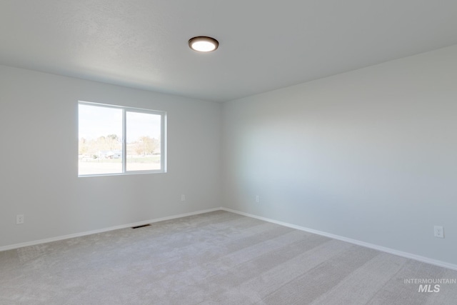 unfurnished room with baseboards, visible vents, and light carpet