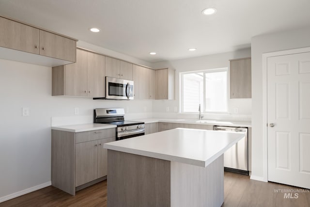 kitchen with light brown cabinetry, stainless steel appliances, light countertops, and wood finished floors