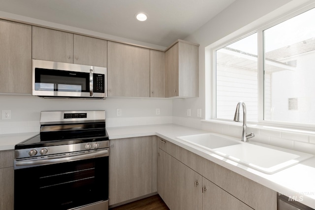 kitchen with a sink, appliances with stainless steel finishes, and light brown cabinetry